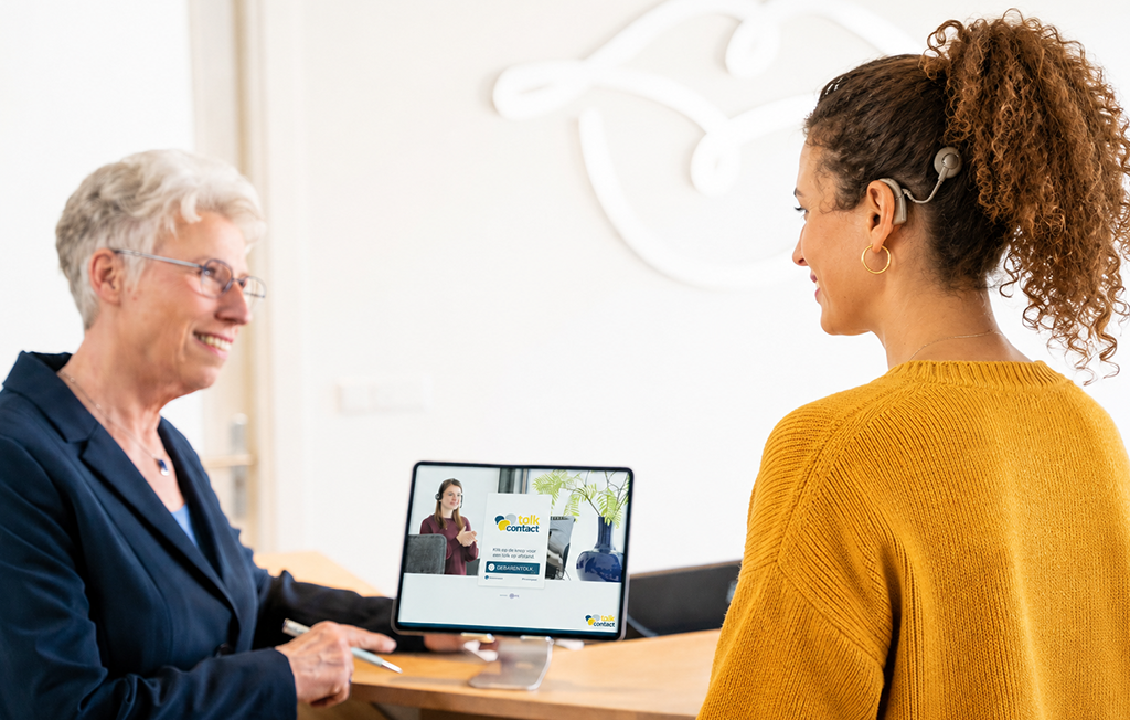 Twee personen voeren gesprek aan de balie met Tolk op afstand via tablet.